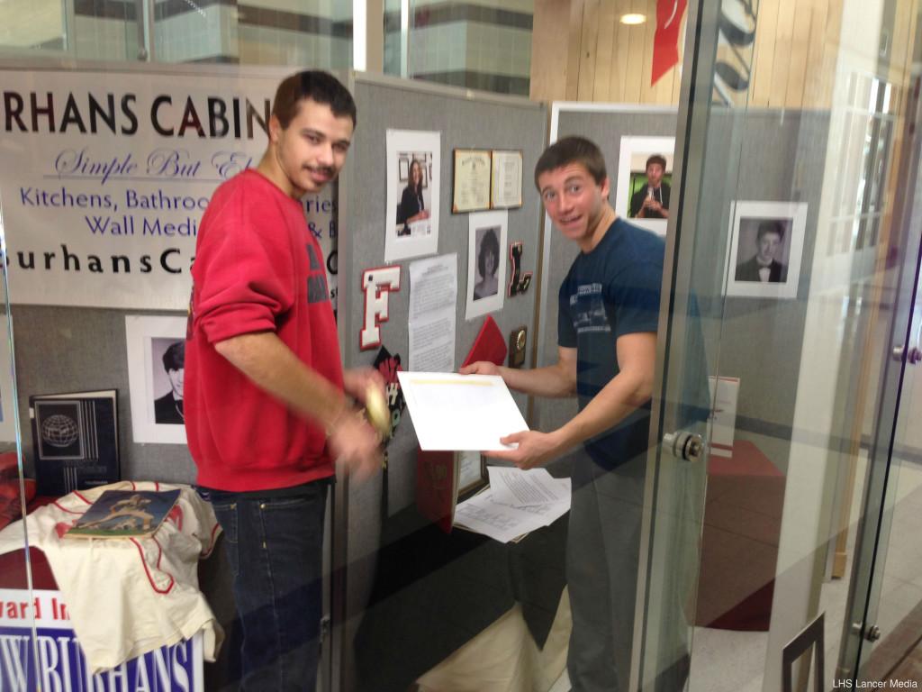 Senior Davey Allison and junior John Gober help with the set up of the Distinguished Graduate display case. The Distinguished Graduate assembly will honor five high achieving graduates on November 26.
