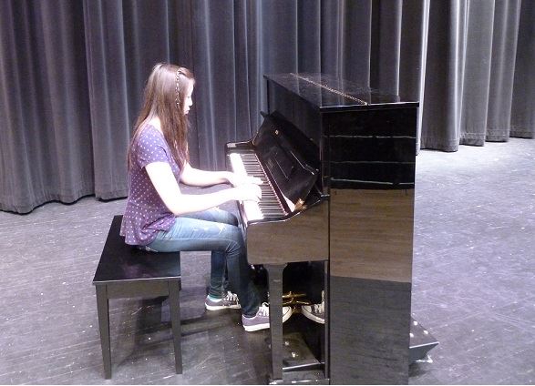Katherine demonstrates her piano abilities for a small group of students at school