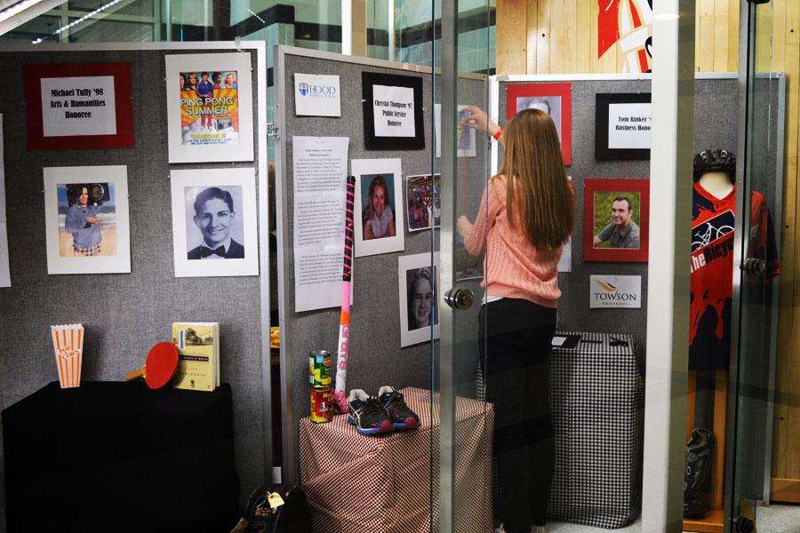 Senior Amy Safsten helps set up the display case featuring the Distinguished Graduate honoree profiles.  