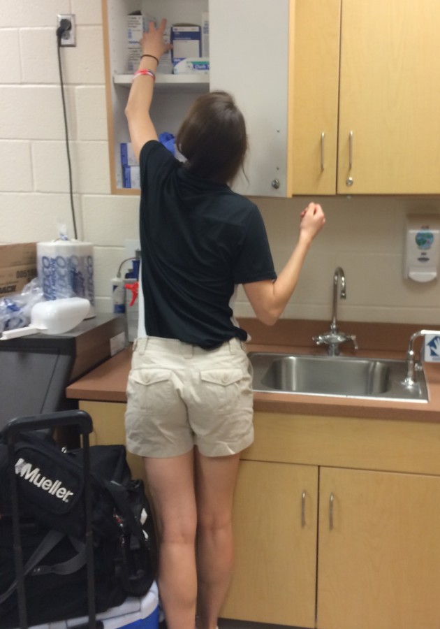 Caroline gathers necessary materials in her office to prepare injured athletes for practice.