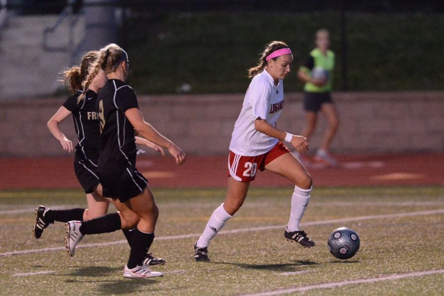 Elizabeth Coletti dribbling pass two Frederick defenders on her way to goal 