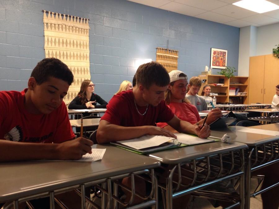 Three senior varsity football players Gary Raney on the left, Ian Faulconer in the middle, and Wade Stieren all participating in their AP composition class.