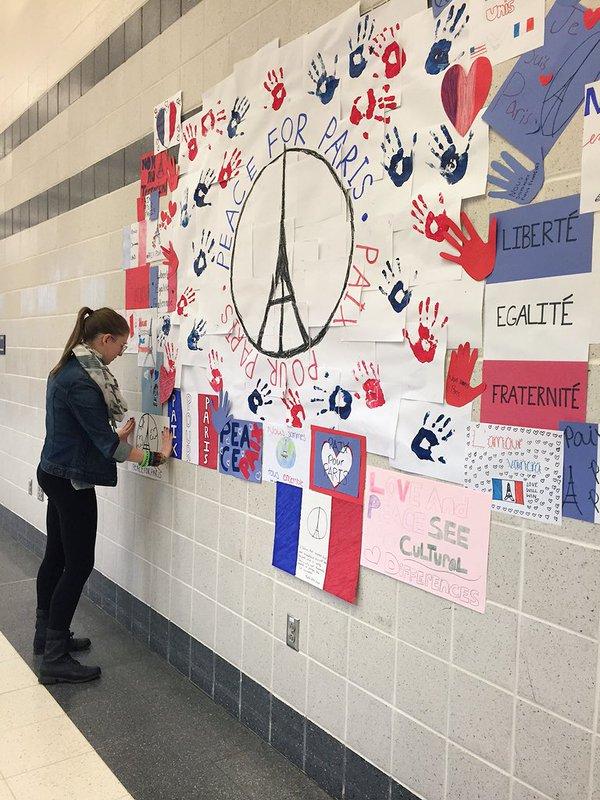 Madeline Wodaski finishes hanging artwork on the French Collage hung in the cafeteria.