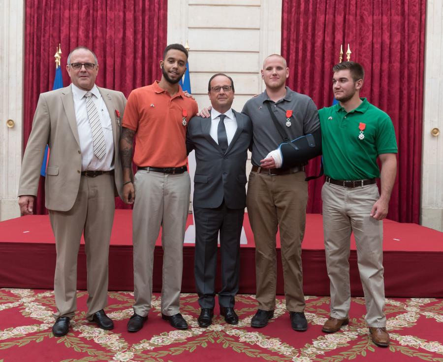 French President Francois Hollande, center, poses with British man Chris Norman, from left, and Americans Anthony Sadler, Spencer Stone and Alek Skarlatos.