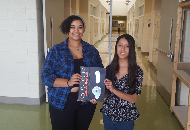 Publications students Brianna Pettaway and Kaila Gordon hold a previous Linganore yearbook, representing the work that their Publications class has completed in the past.