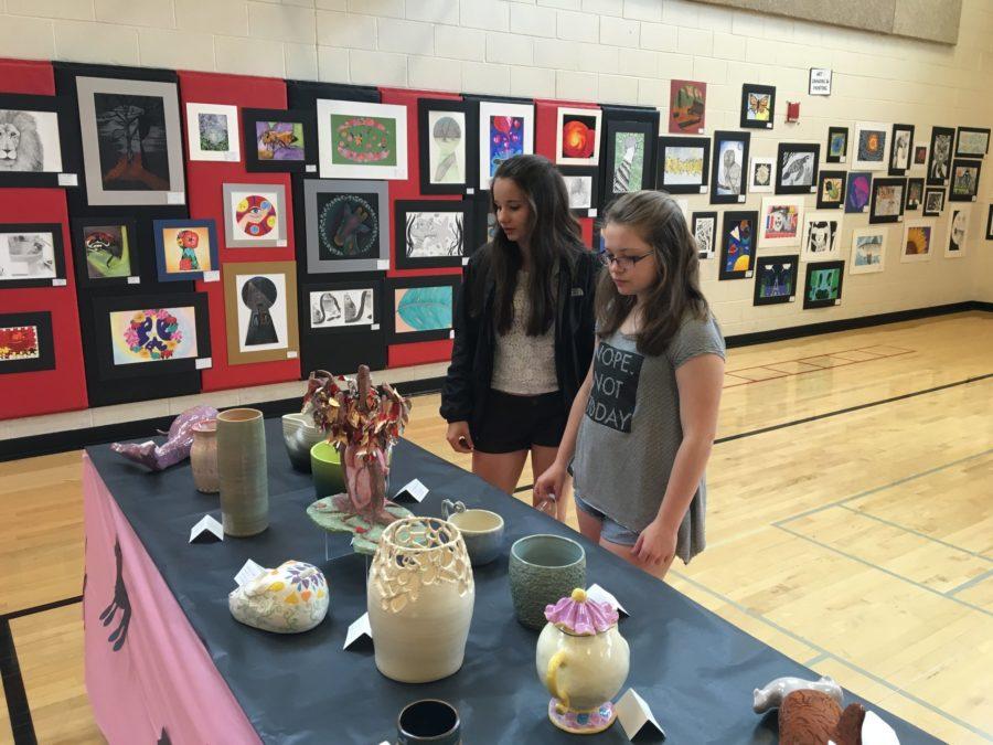 Seniors Bailey Clum and Megan Werner view ceramic pieces during the art show.