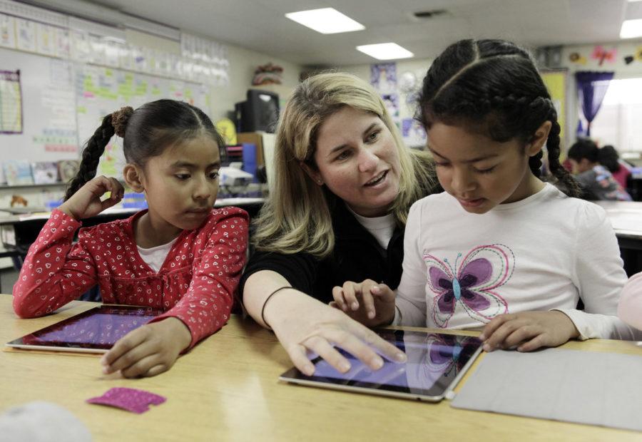 First-grade teacher, Jennifer Finley, teaches Elsi Leon, left, and Anna Lolomanaia how to use the functions of an iPad at Santa Rita Elementary School in Los Altos, California, on Friday, February 17, 2012. Schools are finding the idea of an all-digital classroom attractive, but is still cost prohibitive because of licensing agreements for interactive textbooks. (Gary Reyes/San Jose Mercury News/MCT)
