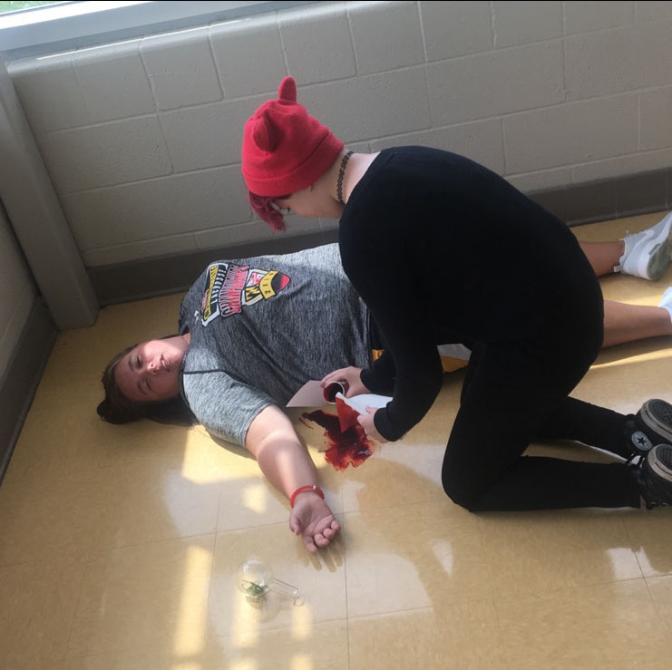 Abby Maloid spreads fake blood around Kelly Rippeon as she acts as the victim in their crime scene. 