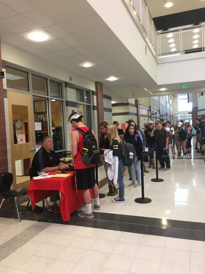 Students buy tickets for the homecoming dance from Mr. Brown.