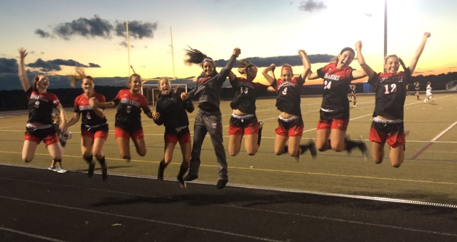 The girls varsity team jump in victory.