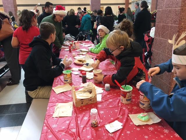 Children use frosting and sprinkles to make their own Christmas cookies. 