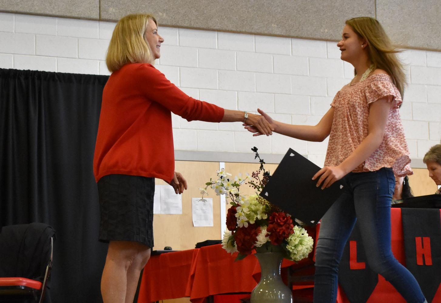Lexi Fowler shakes hands with Principal Nancy Doll.
