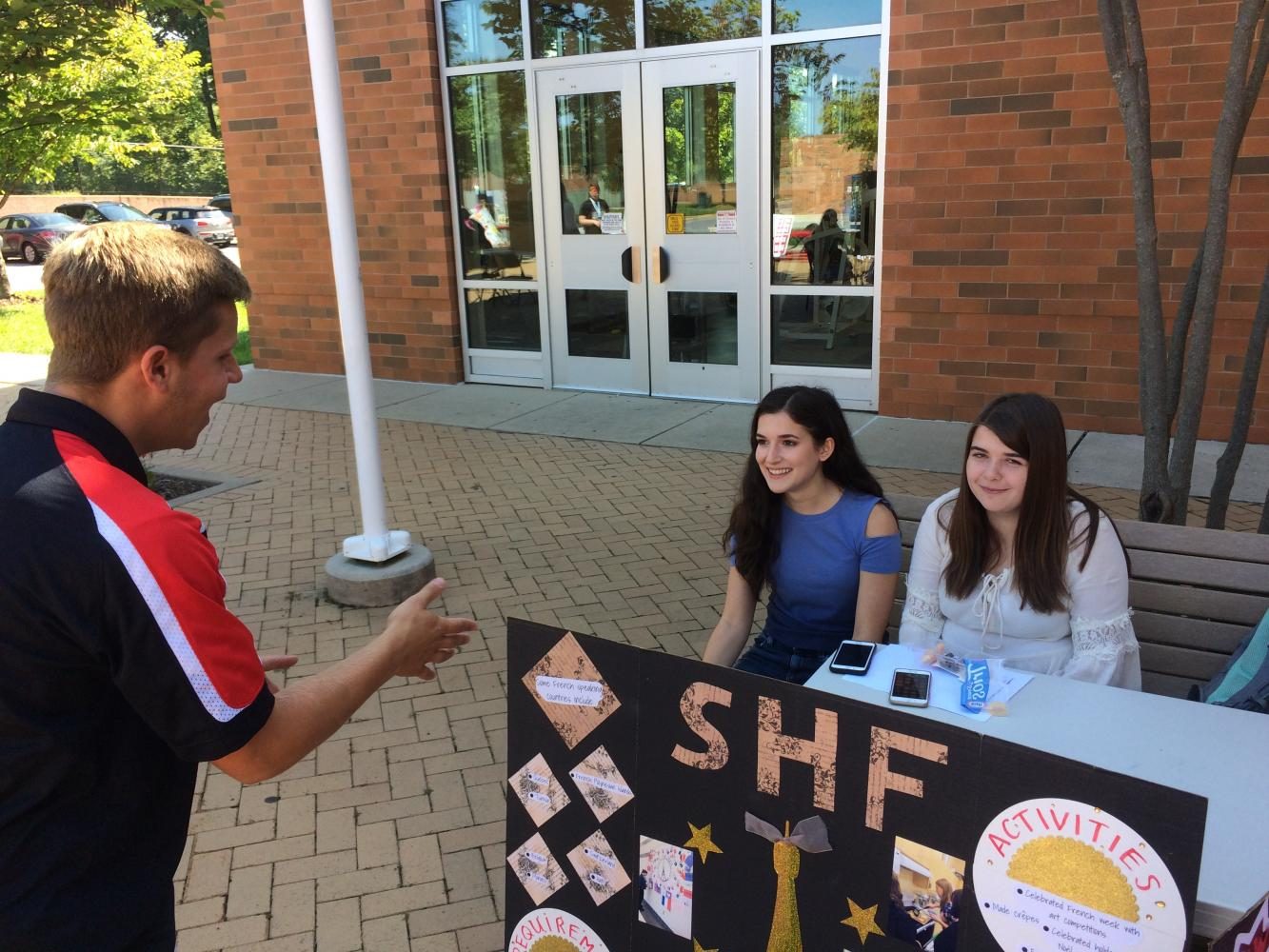 SGA president Jack Dubro talks with French Honor Society president Sophia Schuller and vice president Olivia Hubble about joining their club.