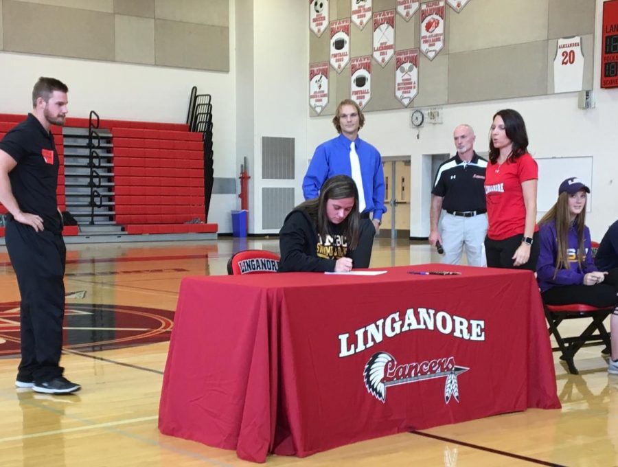 Lily McCoy signs the papers to swim for UMBC in 2018.