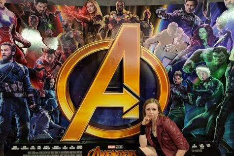 Elizabeth Anderson cosplays Scarlet Witch in front of Avengers: Infinity War poster