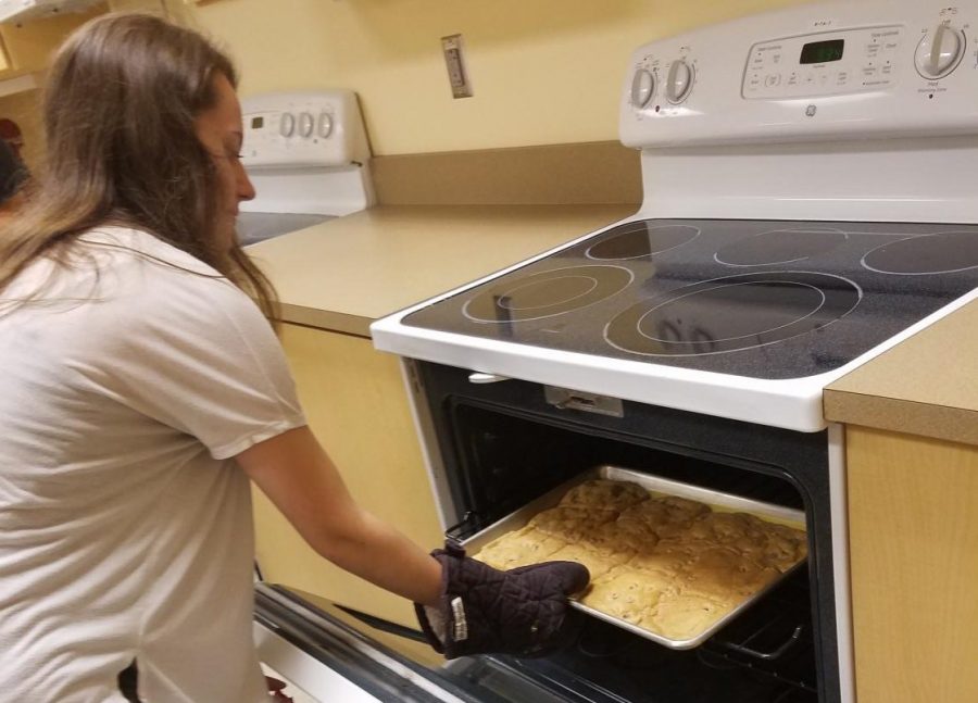 Senior Hanna Dufresne carefully takes cookies out of the oven in Mrs. Lanes Independent Living cooking room.