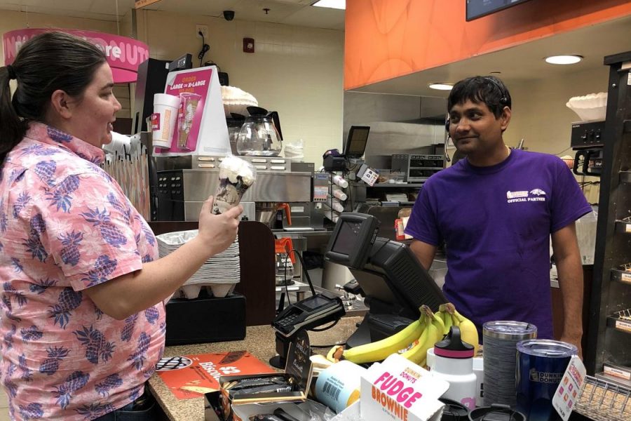 Andi Christ (left) receives a Dunkin Donut order from  employee (right), Alpesh Patel.