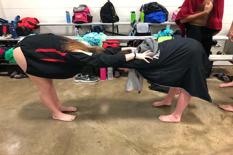 Freshman Emily Lotito and Lyra Garrett stretch their shoulders before their events. 