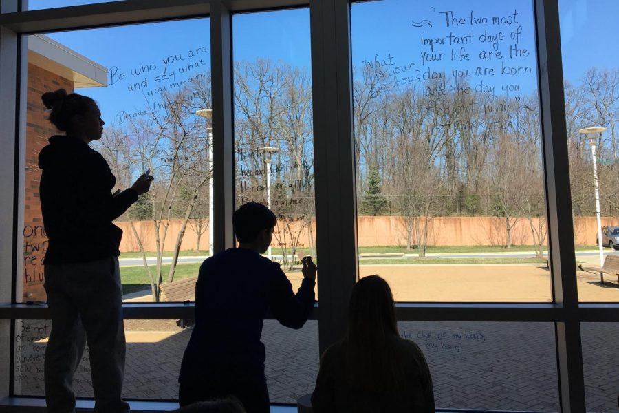National English Honor Society members write poetry on the cafeteria windows. 