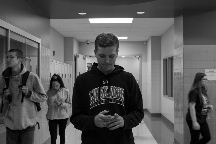 Ethan Butehorn walks through the halls staring at his phone, unaware of whats going on around him.