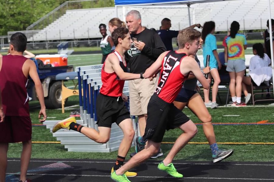 Zack Hunsaker hands the baton to Bailey Spore for the final leg of the 4x800 meter relay.