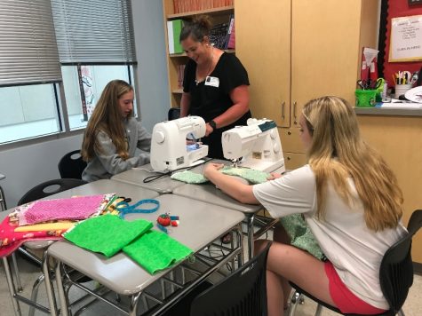 Howard County 4-H Program Adviser Chris Rein teaches Lancer Media members Madeline Williamson and Julie Walker how to sew a pillowcase.