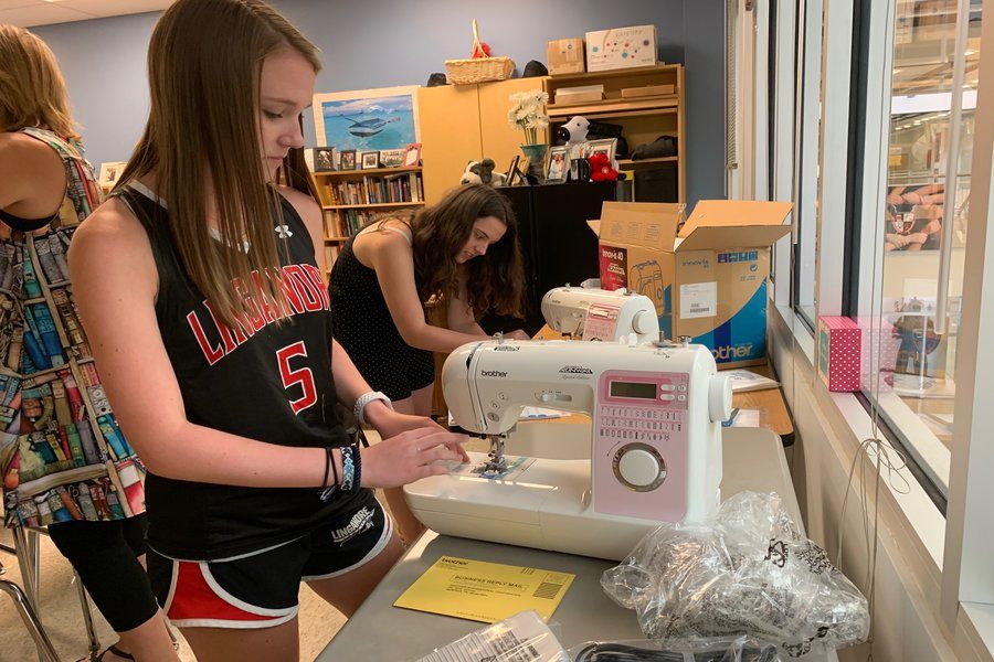 Sierra Rossman and Peyton Johnson prepare new sewing machines for the sew therapy PREP class.