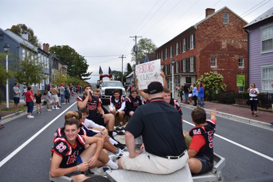 Students on the senior class float wave to fans watching the 2019 homecoming parade.
