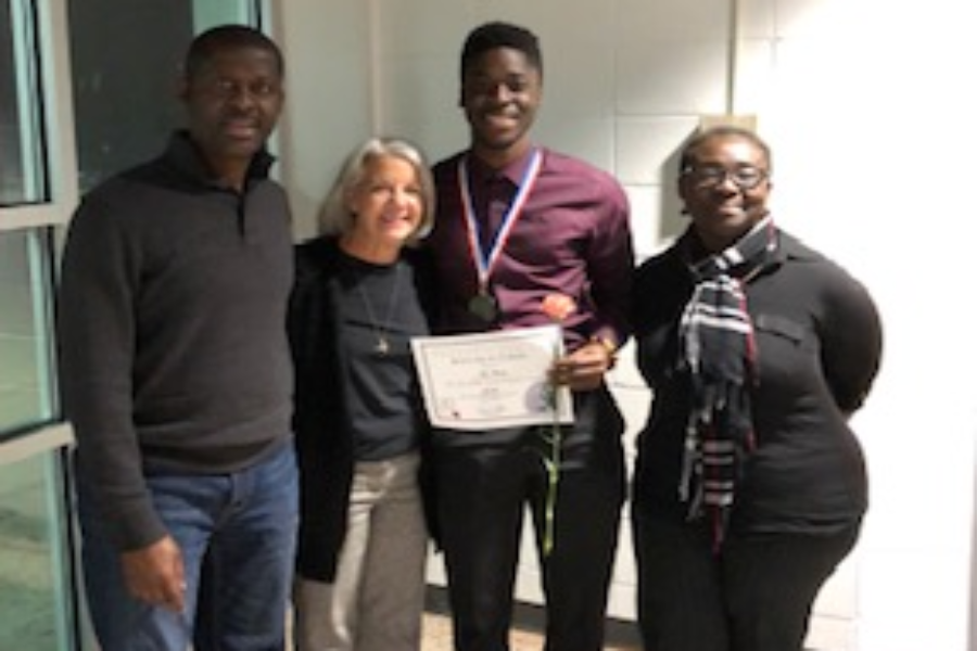 Kojo Benefo poses with his parents and Principal Nancy Doll.
