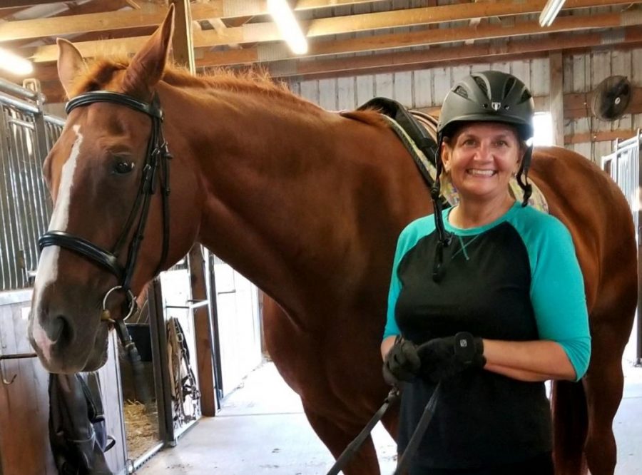 Gayle Blair with her horse in a barn on a beautiful day.