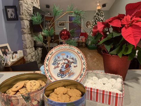 Holiday cookies in Christmas tins surrounded by “Cookies for Santa,” The Peanuts Christmas tree, and a Poinsettia