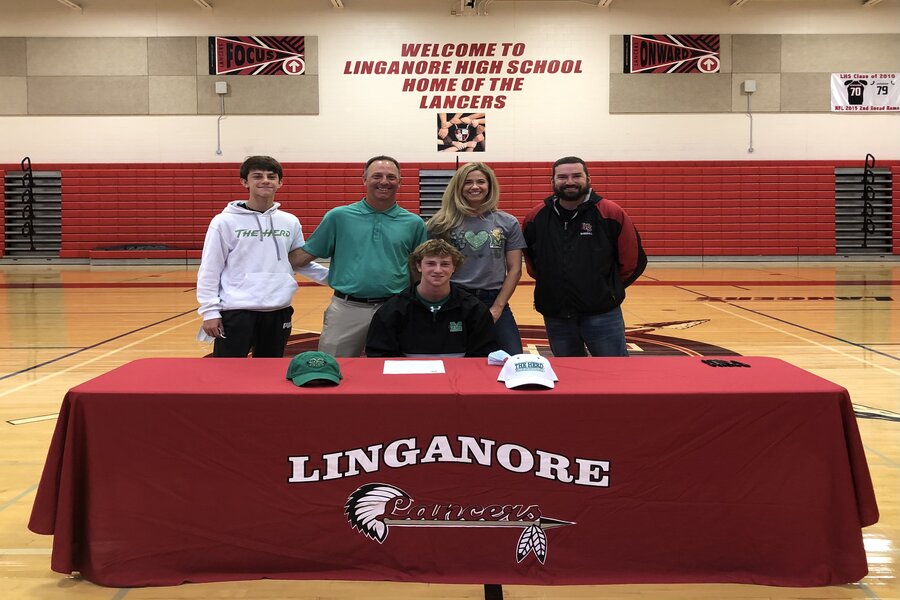 Cam Rokisky smiles at the signing table for a picture with his family and high school head coach David Keiling.
