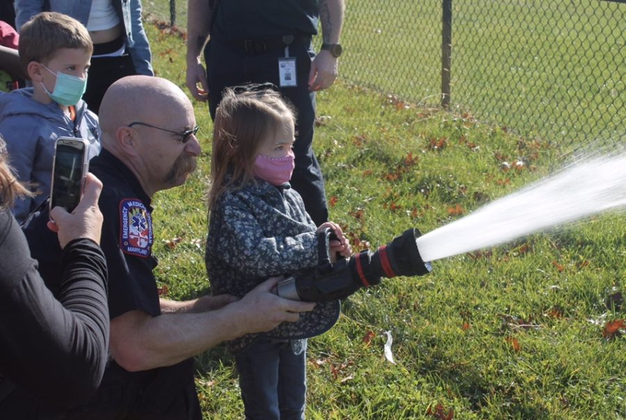 Lily sprays water out of the hose as a fireman lends a helping hand. (Abbey Sovero)