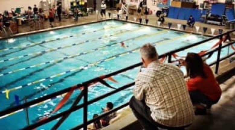 Mike and Shari Lotito watching Emily Lotito swim at a high school meet.