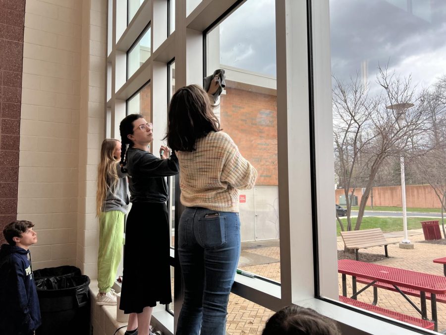 With rain eminent from behind the glass, members of the NEHS, Catarina Brocolino and Genevieve Cretella, write on the windows with dry erase markers.
