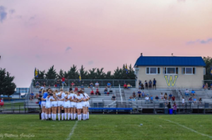 Girls varsity soccer team huddled for team prayer before fall 2021 game.