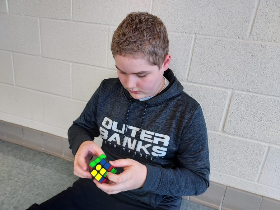 Landon Jones is seen sitting in the school hallway solving a Rubiks cube, which is how he spends much of his downtime at school.