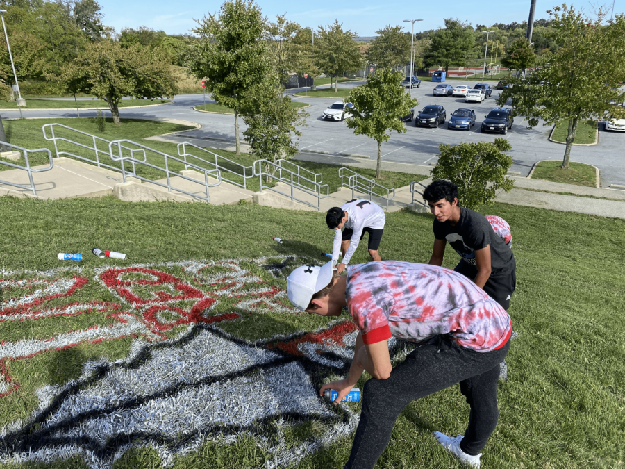 Senior class council members clean up their design by adding outlines and filling in their spear symbol with silver paint.