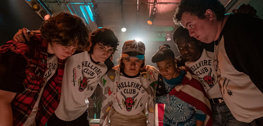 Characters from Stranger Things huddle together to decide what their next move will be during a game of D&D. 