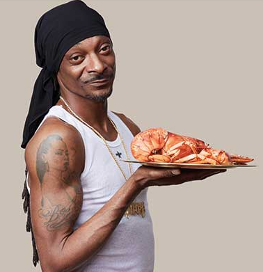 Snoop holding one his lobster made with his recipe in his cook book