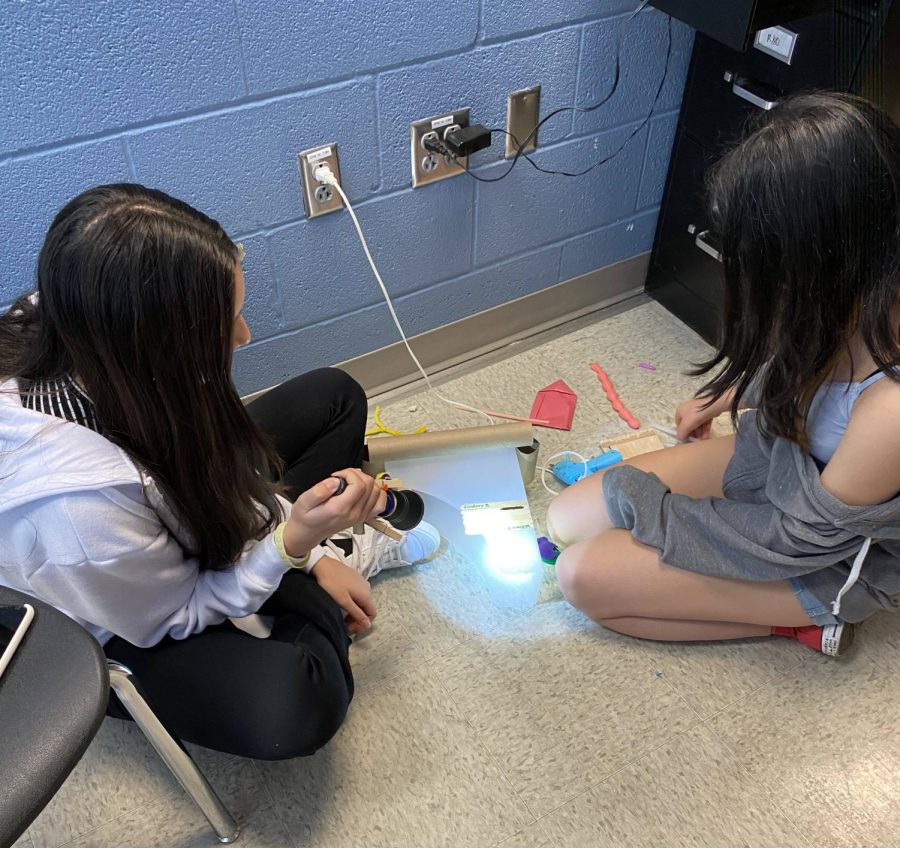 Daniela Castellanos and Emily Maya build a reflective base for their maker project.