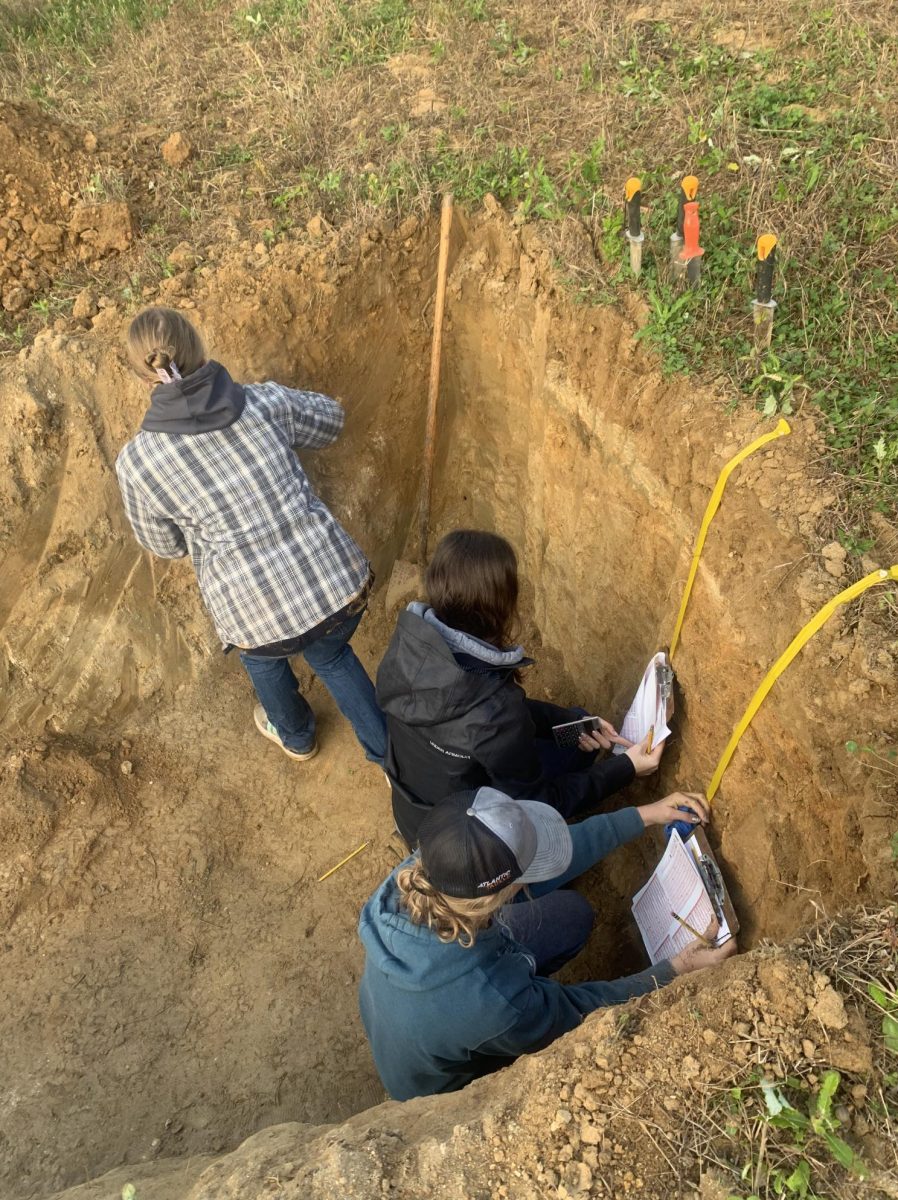Three students are shown practicing their soil judging abilities.
