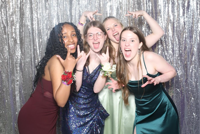 Leila Gibril (12), Mia Lucas (12), Emily Rice (11) and Cara Morgan (11) make silly faces in front of the photobooth backdrop set up for prom photos.