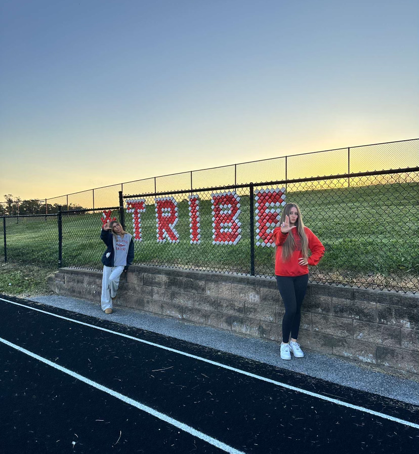 Seniors Gigi Broccolino and Charley Grimet pose up by the Tribe sign to show school spirit.