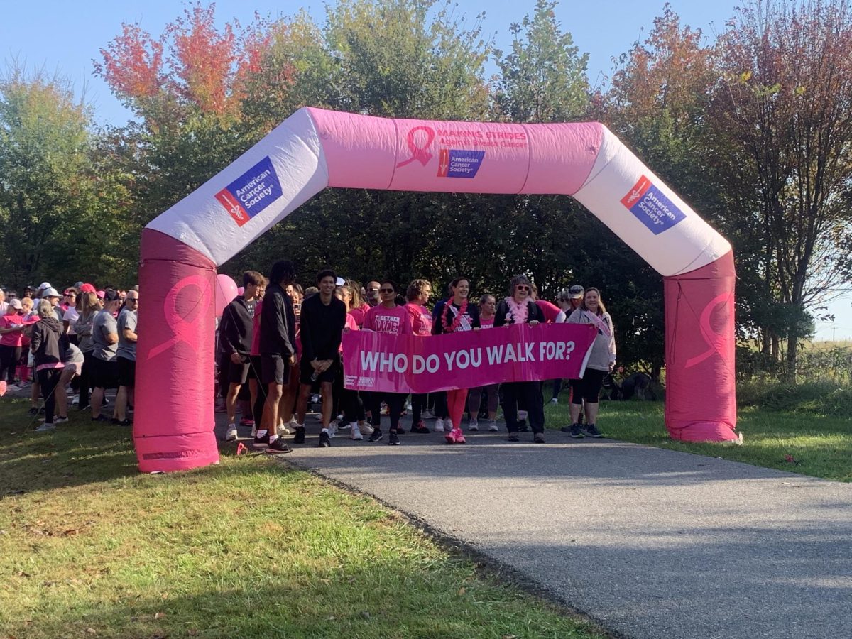 A "Who do you walk for?" sign is held while getting ready to walk for the Making Strides against Breast Cancer.