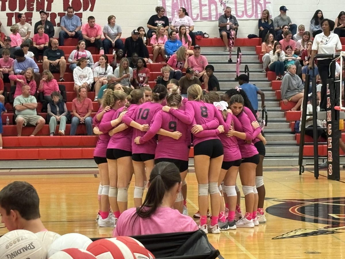 LHS varsity players huddle together before their first set against the Urbana Hawks.