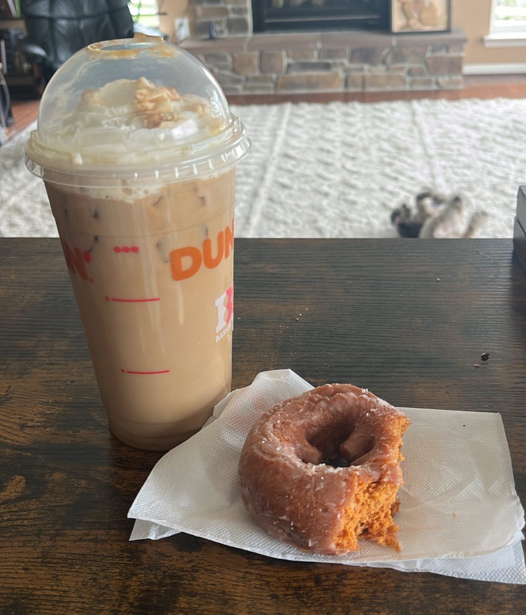 A Dunkin' Donuts pumpkin latte and donut are featured on a table. 