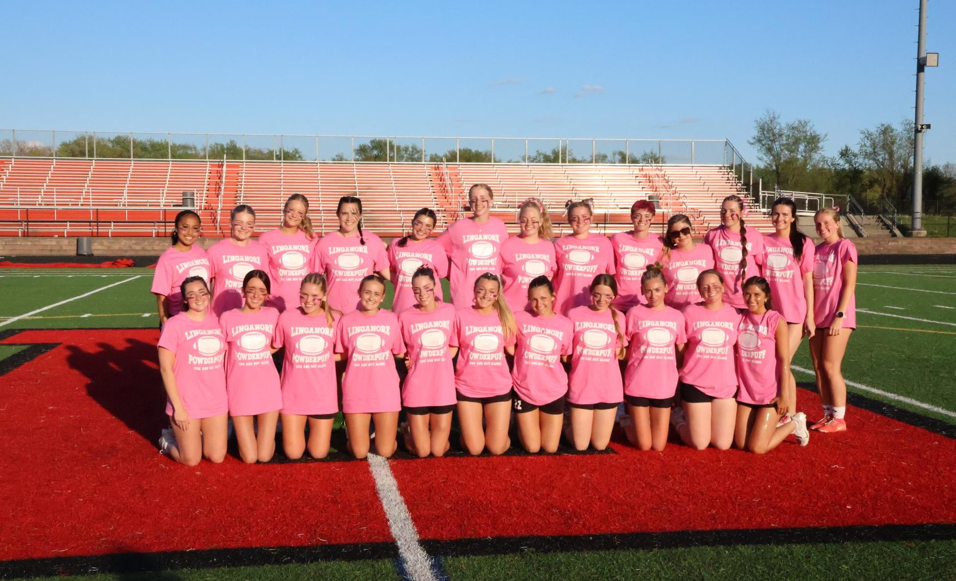 Seniors at Linganore High School kneel and stand posing towards the front before playing in the Powderpuff game. (Photo courtesy of Doug Niemeier)